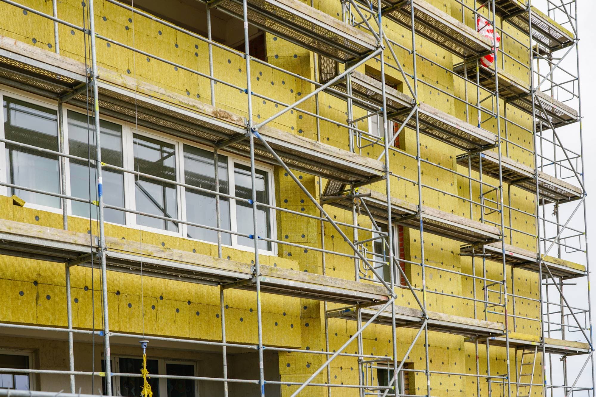 Fassade mit neuer Mineralwolle-Dämmung hinter dem Gerüst